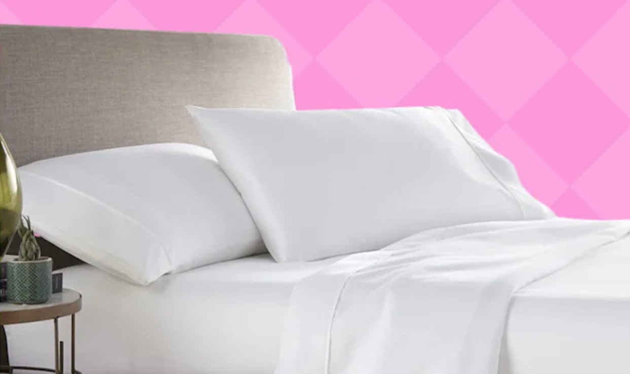 A made bed with white sheets, 2 white pillows, headboard and nightstand