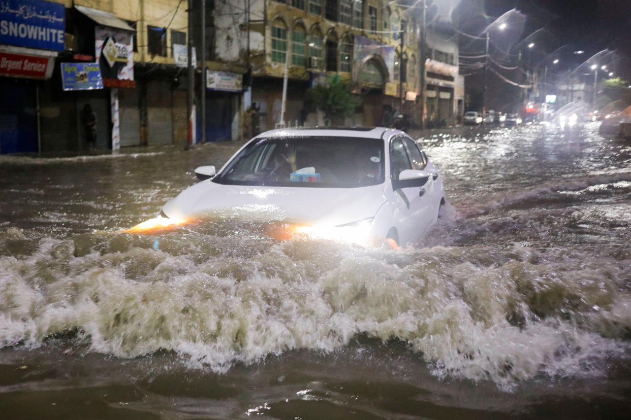 A car creates waves as it drives along a flooded street in Karachi, Pakistan.