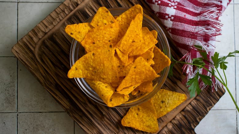 A bowl of Doritos on a cutting board