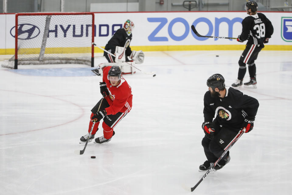 Chicago Blackhawks center Drake Caggiula, left, controls the puck against defenseman Brent Seabrook, right, during NHL hockey practice at Fifth Third Arena on Monday, July 13, 2020, in Chicago. (AP Photo/Kamil Krzaczynski)