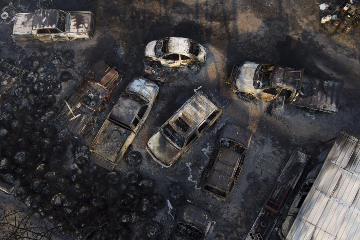 Charred vehicles sit at what’s left of an auto body shop that was burned by the Smokehouse Creek Fire