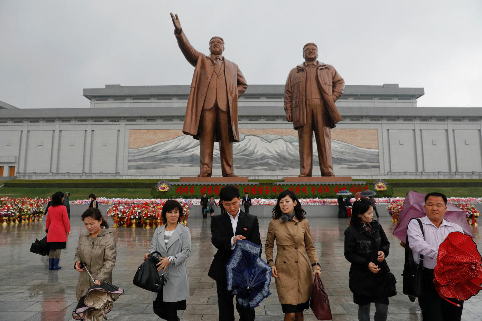 People walk after paying their respects at the statues of North Korea founder Kim Il Sung (L) and the late leader Kim Jong Il in Pyongyang, April 14, 2017.