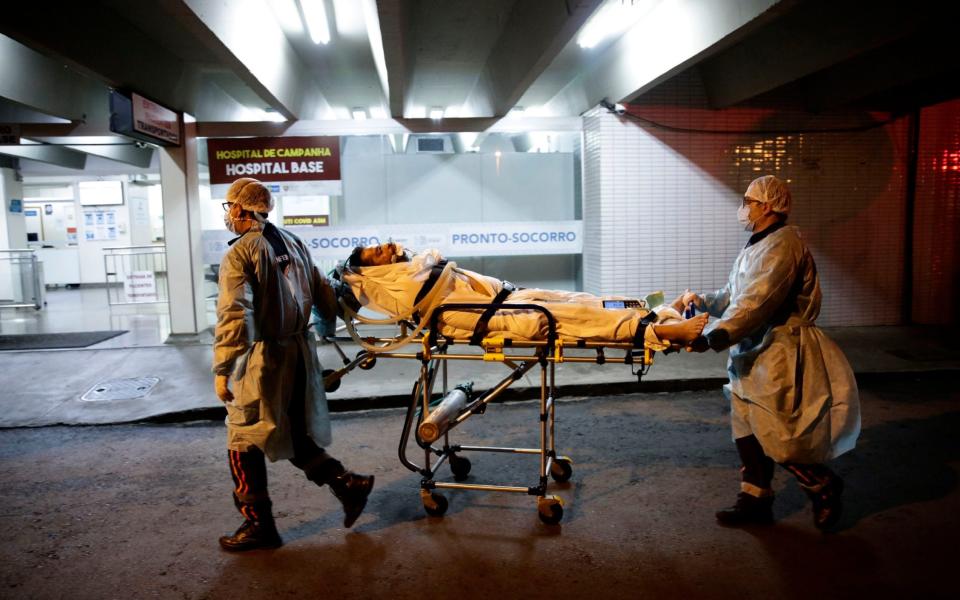 Healthcare workers of the public Mobile Emergency Service bring a patient suspected of suffering from COVID-19 to the Base Public Hospital - AP Photo/Eraldo Peres
