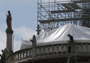 FILE - In this April 26, 2019 file photo, a worker checks the waterproof tarps on Notre Dame cathedral in Paris. The billionaire French donors that publicly promised flashy donations totalling hundreds of millions to restore Notre Dame, have not yet paid a penny toward the restoration of the French national monument, according to church and business officials. Instead, it's mainly American citizens that have footed the bills and paid salaries for the up to 150 workers employed by the cathedral since the April 15 fire. (AP Photo/Michel Euler, File)