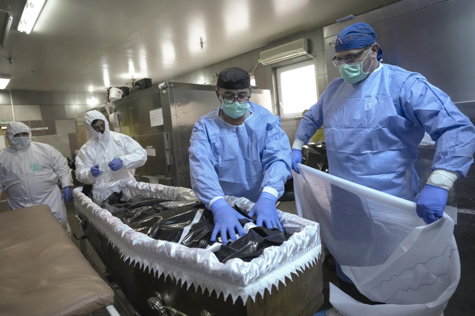 FILE - Members of the medical staff place the body of a COVID-19 victim in a coffin together with funeral house employees at the University Emergency Hospital morgue in Bucharest, Romania, Monday, Nov. 8, 2021. (AP Photo/Vadim Ghirda, File)