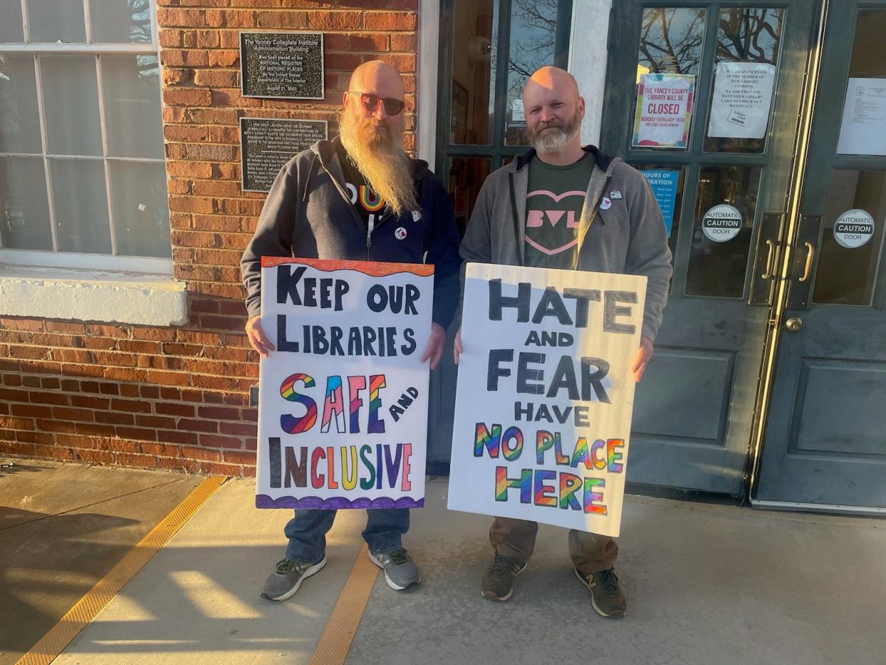 Pictured are two Yancey County residents holding signs in support of the Avery-Mitchell-Yancey Regional Library Board at a February Yancey County Public Library Advisory Board meeting at the Yancey County Library in Burnsville.