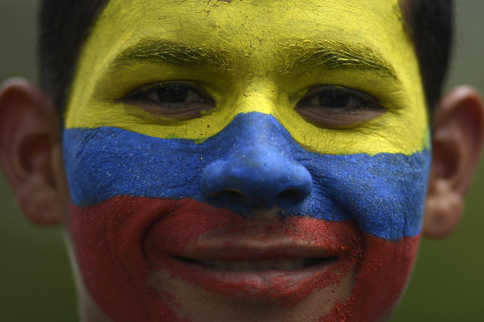 A government supporter, his face painted with the colors of the national flag, smiles during a march marking Youth Day, in Caracas, Venezuela, Saturday, Feb. 12, 2022. The annual holiday commemorates the young people who accompanied heroes in the battle for Venezuela's independence. (AP Photo/Matias Delacroix)