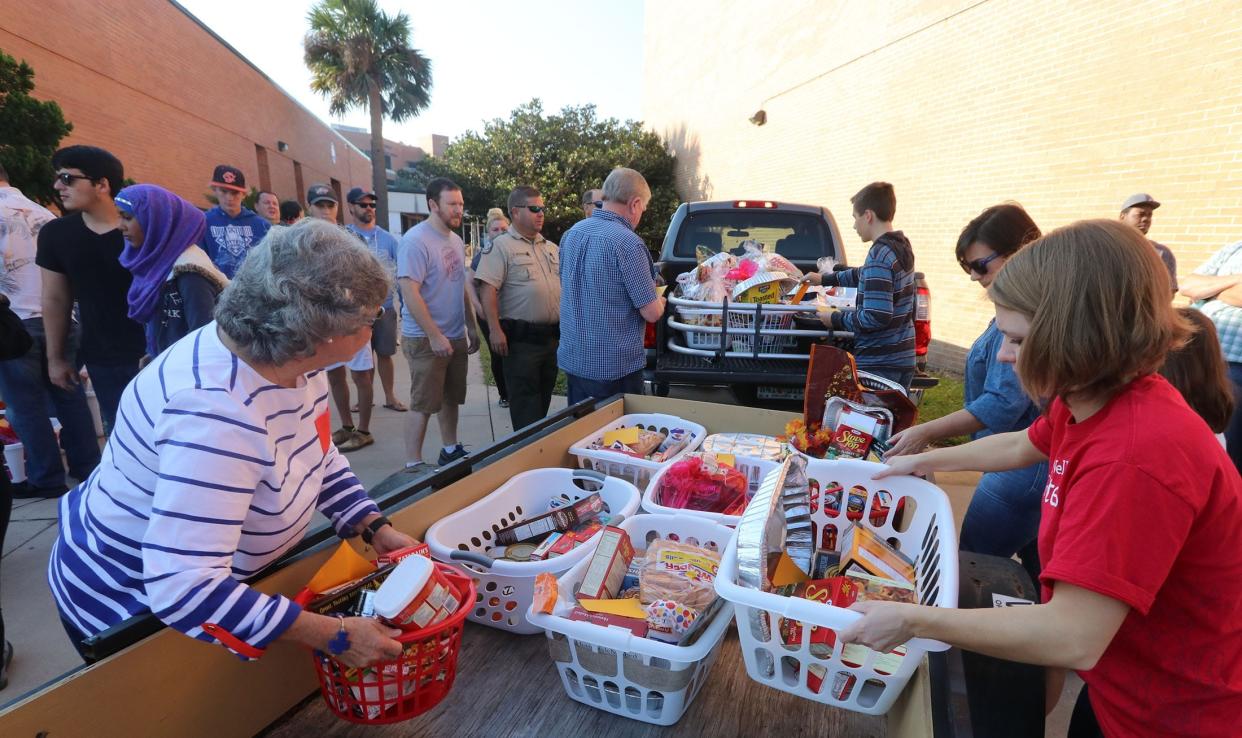 Volunteers transfer baskets of Thanksgiving food and supplies from a Daytona State College parking lot into their vehicles as part of the Volusia Thanksgiving Basket Brigade.