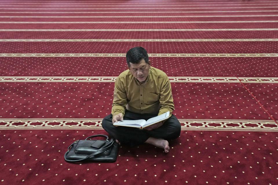 A man reads the holy book of Quran at Istiqlal Mosque whose electricity partially come from solar power in Jakarta, Indonesia, Wednesday, March 29, 2023. A major renovation in 2019 installed upwards of 500 solar panels on the mosque's expansive roof, now a major and clean source of Istiqlal's electricity. (AP Photo/Tatan Syuflana)