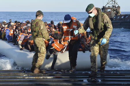 Royal Marines lead migrants to safety on a landing craft of HMS Bulwark after their rescue from the Mediterranean between Italy and North Africa, May 13, 2015. REUTERS/Crown Copyright/Carl Osmond/Handout via Reuters