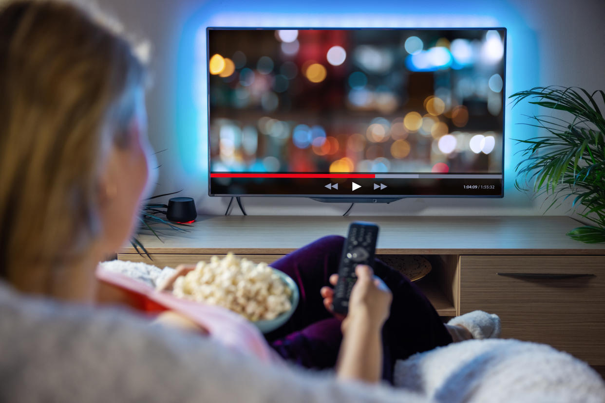 Female relaxing at home in evening and watching TV