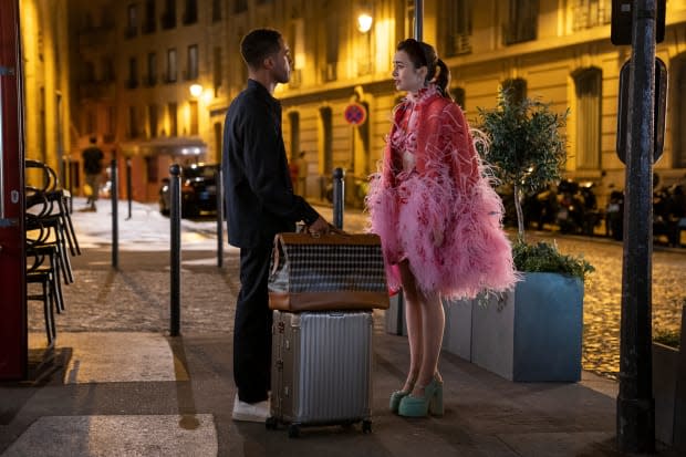 Alfie (Lucien Laviscount) confronts a post-dinner Emily (Lily Collins), in a custom cape, over a Magda Butrym dress, with custom Christian Louboutin platforms.<p>Photo: Stéphanie Branchu/Courtesy of Netflix</p>
