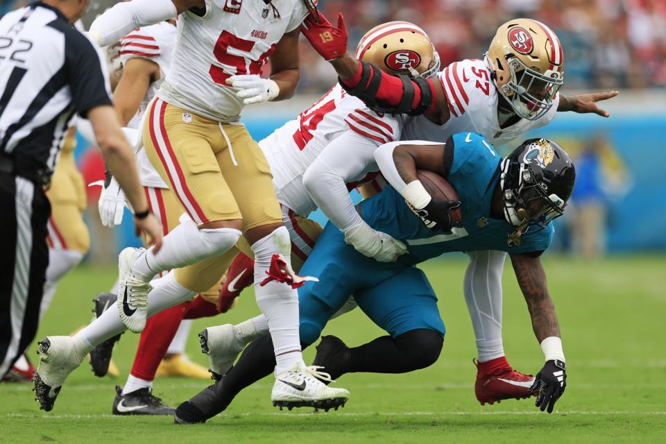 Jacksonville Jaguars running back Travis Etienne Jr. (1) is tackled by San Francisco 49ers linebacker Dre Greenlaw (57) and defensive end Clelin Ferrell (94) during the first quarter of an NFL football game Sunday, Nov. 12, 2023 at EverBank Stadium in Jacksonville, Fla. [Corey Perrine/Florida Times-Union]