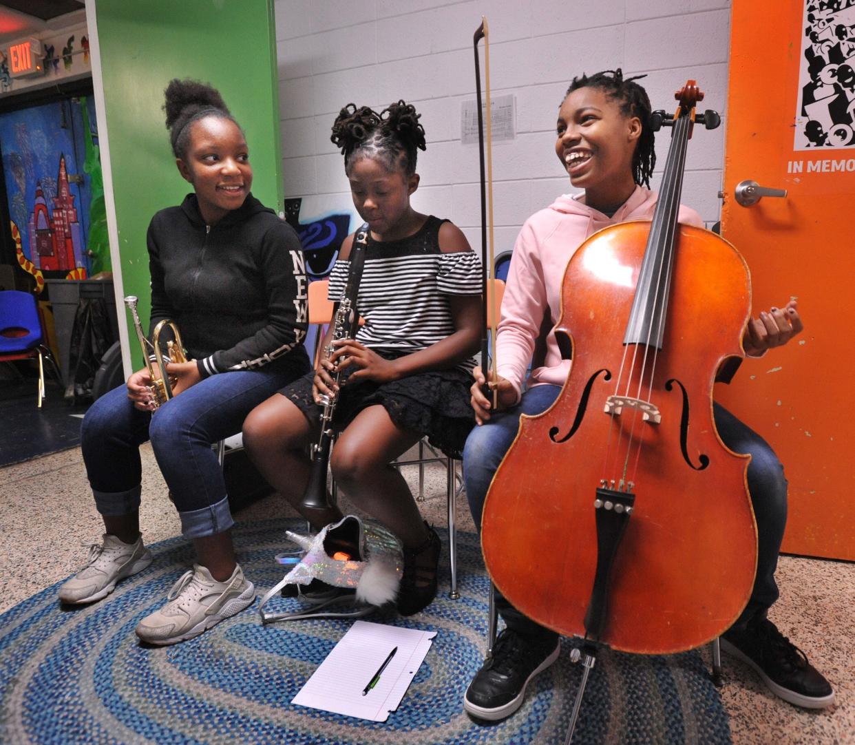 Trumpet player Jordyn Sinclair, from left, and clarinet player Marlee Glover listen as cello player Jaida Ings talks about music at the Don't Miss a Beat community center in 2018. The University of North Florida School of Music provides student mentors to teach children about music and art.
