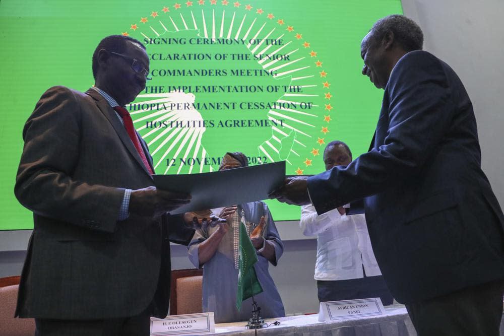 Chief of Staff of Ethiopian Armed Forces Field Marshall Birhanu Jula, left, and Head of the Tigray Forces Lieutenant General Tadesse Werede, right, exchange signed copies of an agreement, at Ethiopian peace talks in Nairobi, Kenya Saturday, Nov. 12, 2022. (AP Photo/Brian Inganga)
