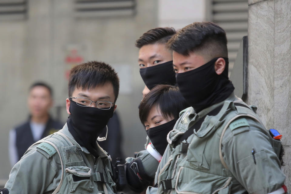 Riot police stand outside of a polling place in Hong Kong, Sunday, Nov. 24, 2019. Voting was underway Sunday in Hong Kong elections that have become a barometer of public support for anti-government protests now in their sixth month. (AP Photo/Kin Cheung)