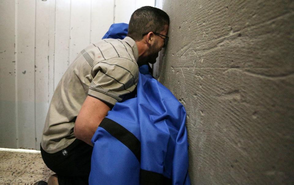 A man grieves near a wall.