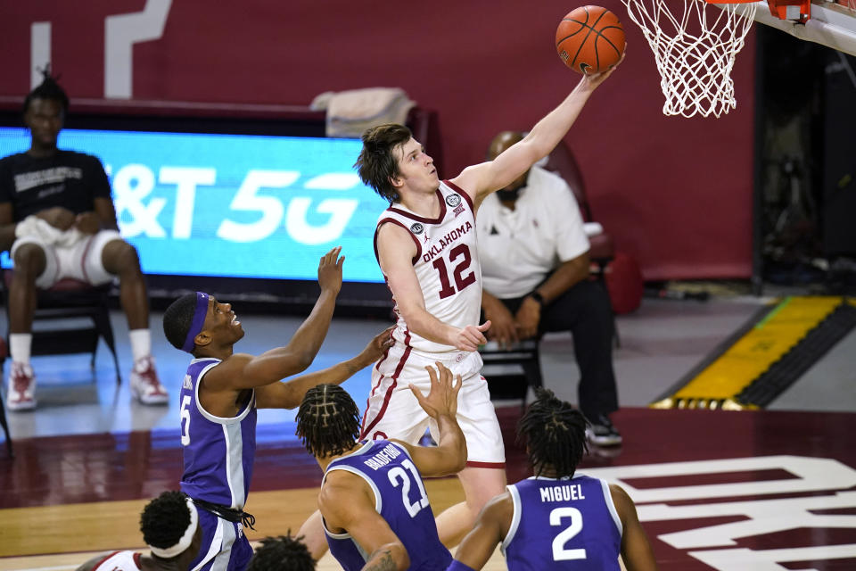 Oklahoma guard Austin Reaves (12) goes to the basket in front of Kansas State guard Rudi Williams (5), forward Davion Bradford (21) and guard Selton Miguel (2) during the second half of an NCAA college basketball game Tuesday, Jan. 19, 2021, in Norman, Okla. (AP Photo/Sue Ogrocki)