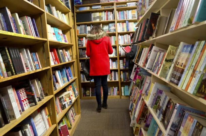 A shopper browses among the narrow rows of books