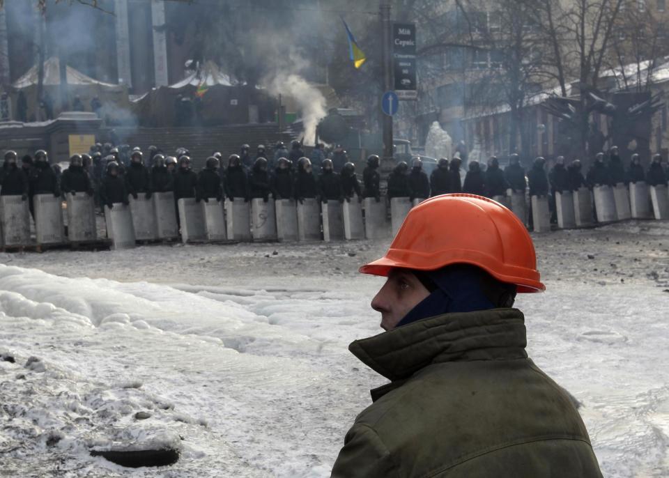 A protester guards the barricade in front of riot police in Kiev, Ukraine, Saturday, Feb. 1, 2014. Ukraine's embattled president Viktor Yanukovych is taking sick leave as the country's political crisis continues without signs of resolution. (AP Photo/Sergei Chuzavkov)