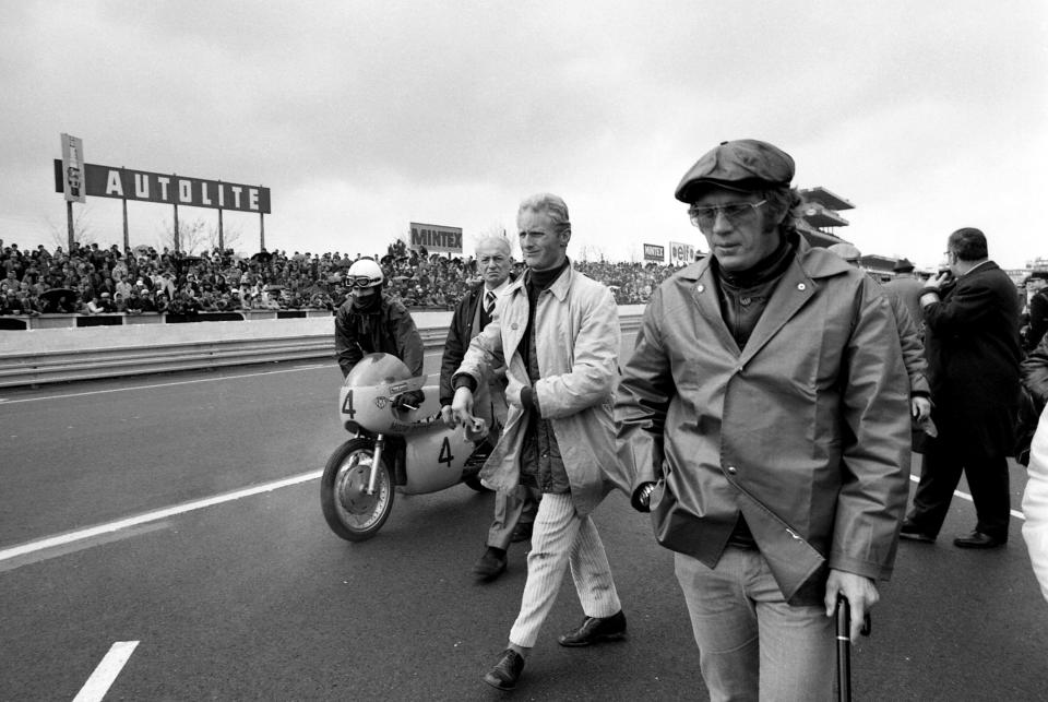 FILE - In this April 13, 1970, file photo, actor Steve McQueen, foreground, visits Le Mans in France. McQueen was at the height of his career (and an actual racer) when he decided to make the ultimate racing film centered on the 24 Hours of Le Mans. "Steve McQueen: The Man & Le Mans" is a 2015 documentary of McQueen's making of the film "Le Mans." (AP Photo/Michel Lipchitz, File)