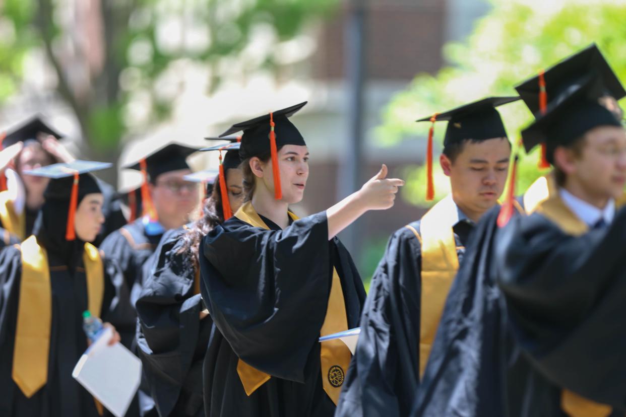 A candidate for graduation tries to inform her family where the commencement is being held as she marchs from the Armory to Elliott Hall of Music to begin Purdue University's 2022 Spring Commencement on May 13, 2022.