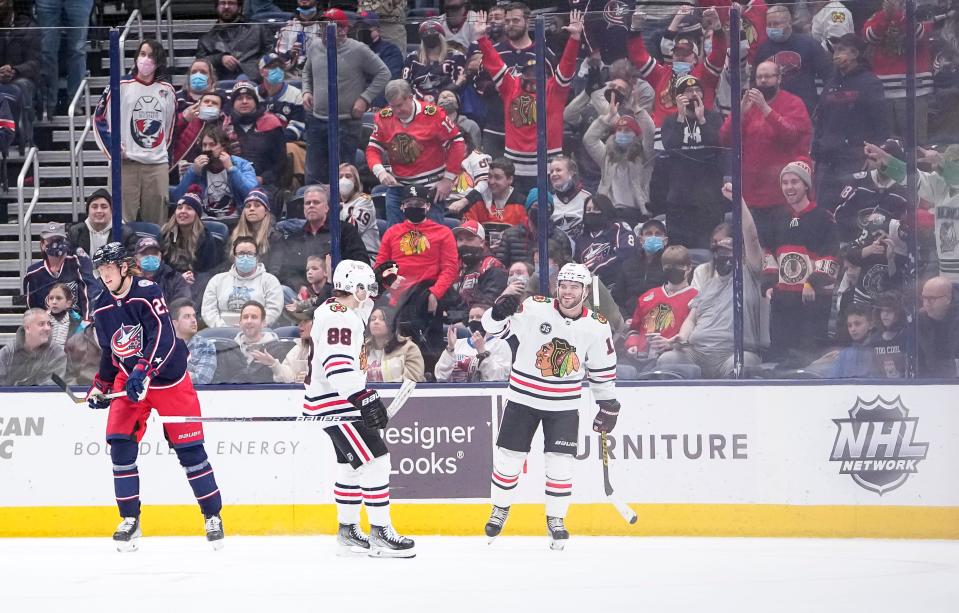 Chicago Blackhawks left wing Alex DeBrincat (12) celebrates an empty-net goal with right wing Patrick Kane (88) beside Columbus Blue Jackets left wing Patrik Laine (29) during the third period of the NHL hockey game at Nationwide Arena in Columbus on Jan. 11, 2022. The Blackhawks won 4-2.