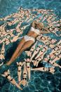 <p>Jayne Mansfield poses on an inflatable raft surrounded by bottles shaped like bikini-clad versions of herself in 1957.</p>