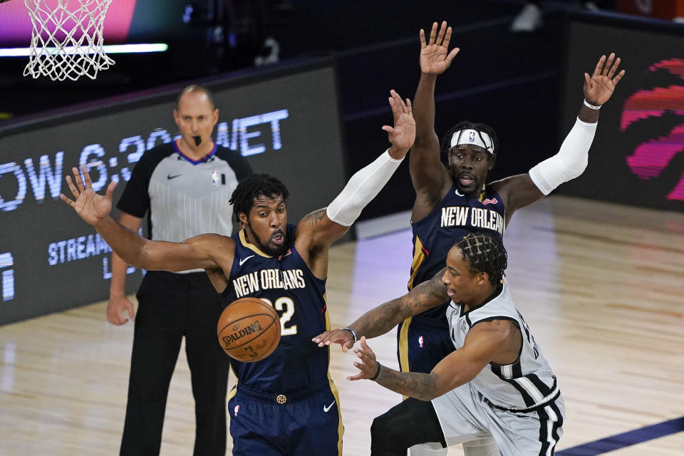 San Antonio Spurs' DeMar DeRozan, front right, passes the ball past New Orleans Pelicans center Derrick Favors, left, and guard Jrue Holiday, back, dunring the second half of an NBA basketball game, Sunday, Aug. 9, 2020, in Lake Buena Vista, Fla. (AP Photo/Ashley Landis, Pool)
