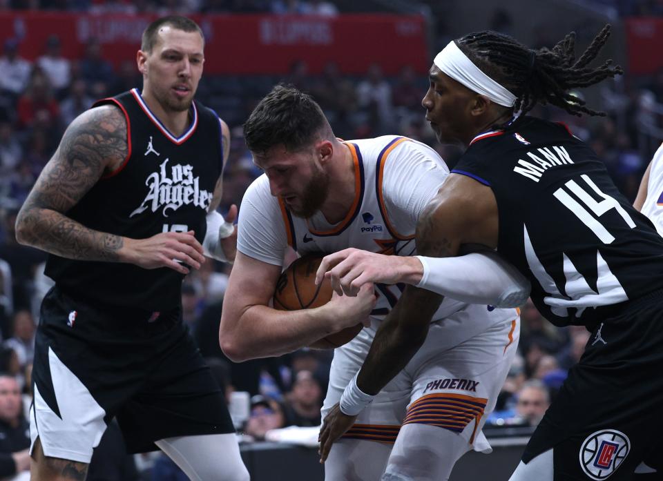 Jusuf Nurkic #20 of the Phoenix Suns protects a rebound from Terance Mann #14 and Daniel Theis #10 of the LA Clippers during the first half at Crypto.com Arena on April 10, 2024 in Los Angeles, California.