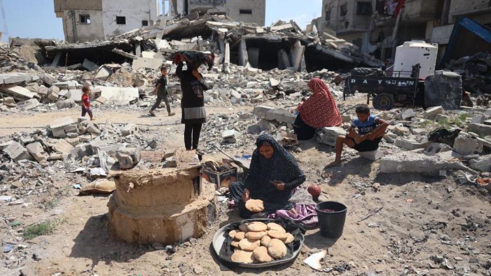 A Palestinian woman bakes bread amid the rubble of destroyed buildings in the southern Gaza town of Khan Younis (June 30, 2024)