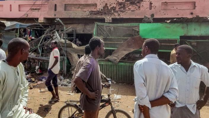 People walk past a bullet-riddled building in a shell-hit market in southern Khartoum - Thursday, June 1, 2023