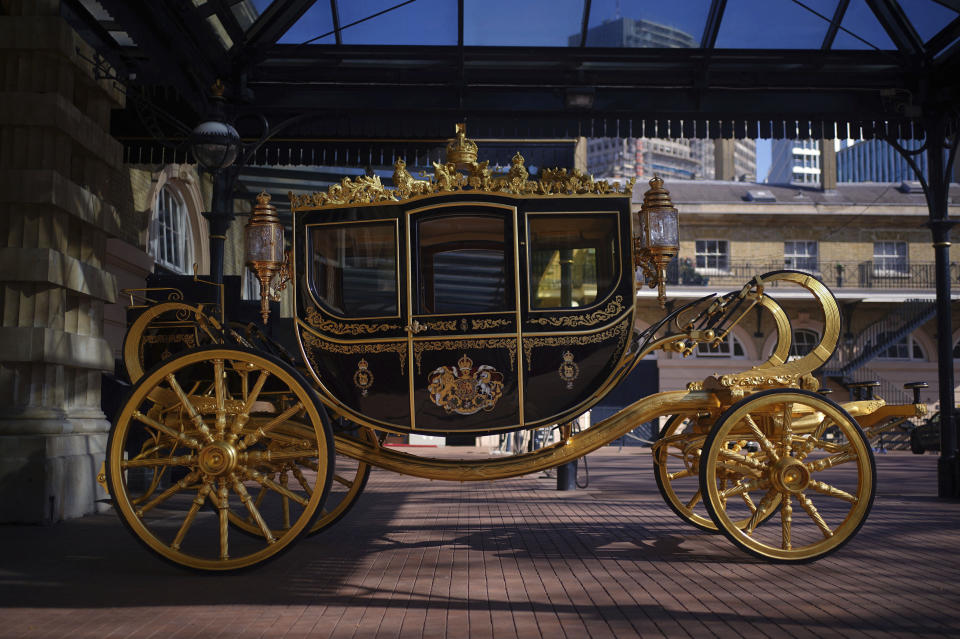 The Diamond Jubilee State Coach on display at the Royal Mews in Buckingham Palace, London, Tuesday April 4, 2023, in which King Charles III and the Queen Consort will travel to the coronation. King Charles III is taking a short cut and smoother ride to Westminster Abbey, trimming the procession route his mother took in 1953 as he aims for a more modest coronation that will include some modern touches, Buckingham Palace said Sunday April 9, 2023. (Yui Mok/PA via AP)