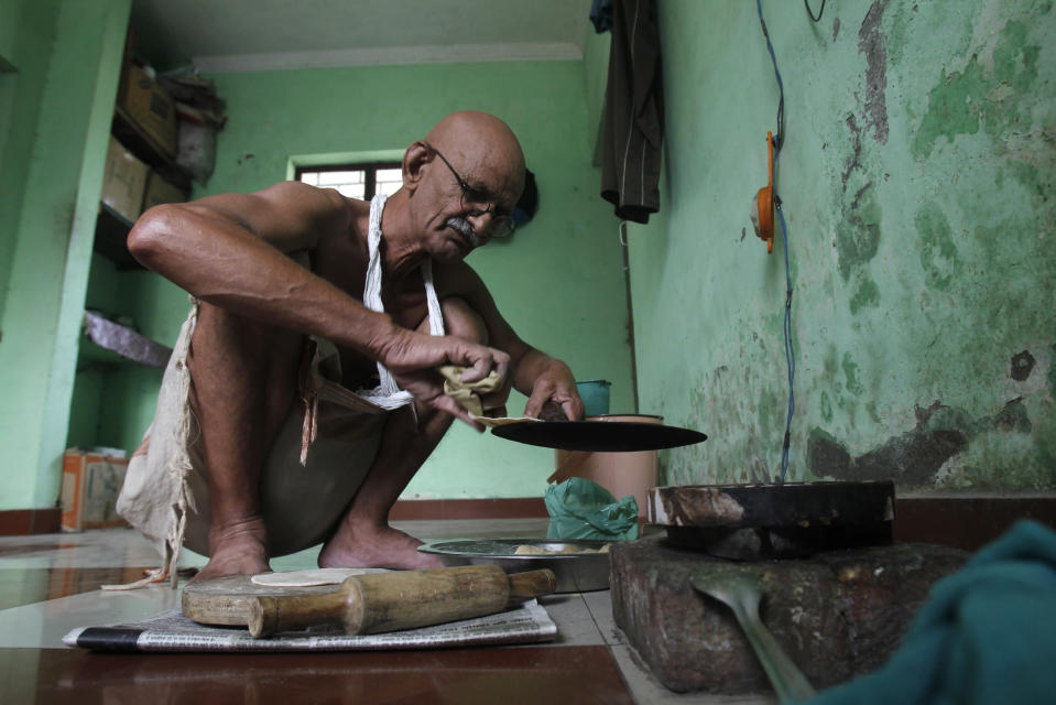 Mahesh Chaturvedi, who dresses up like Mahatma Gandhi, cooks lunch at his residence in the outskirts of New Delhi