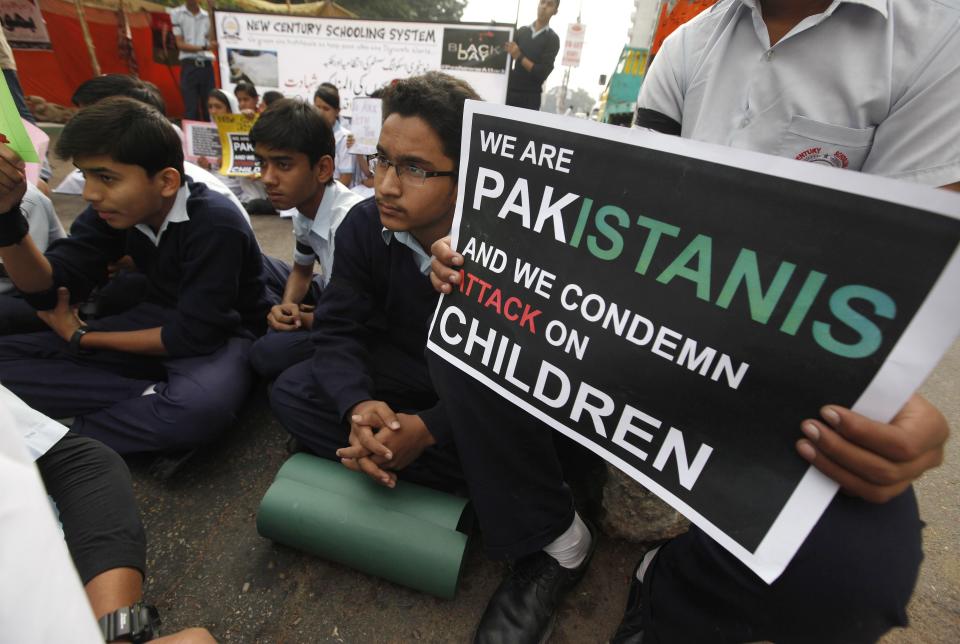 Students sit and hold placards for the victims of the Taliban attack on the Army Public School in Peshawar, along a road in Karachi December 19, 2014. At least 132 students and nine staff members were killed on Tuesday when Taliban gunmen broke into the school and opened fire, witnesses said, in the bloodiest massacre the country has seen for years. REUTERS/Akhtar Soomro (PAKISTAN - Tags: CRIME LAW EDUCATION CIVIL UNREST)