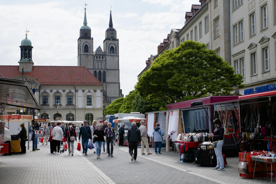 People walk over the market in the federal state Saxony-Anhalt's capital Magdeburg, Germany, Wednesday, June 2, 2021. The state vote on Sunday, June 6, 2021 is German politicians' last major test at the ballot box before the national election in September that will determine who succeeds Chancellor Angela Merkel. (AP Photo/Markus Schreiber)