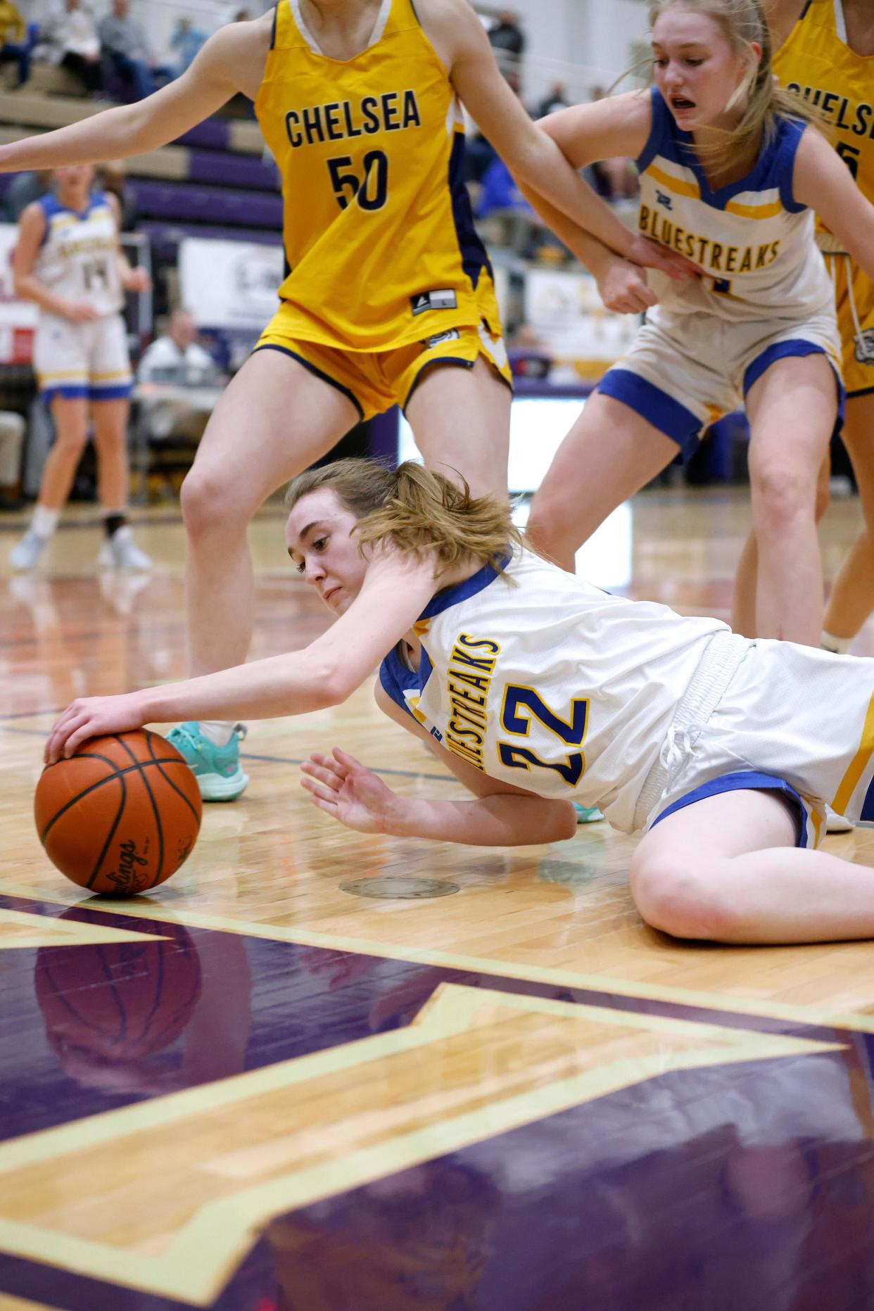 Ida's MacKenzie LaRoy, bottom, hits the floor while trying to corral a loose ball against Chelsea's Grace-Miriam Ratliff, left, Ida's Reese Hennessey, Tuesday, March 7, 2023, at Fowlerville High School.