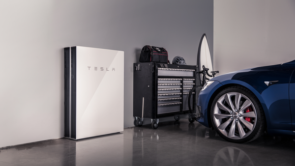 A Tesla Powerwall 2 in a garage, next to a Tesla vehicle