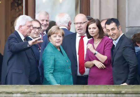 Leader of the German Green Party Cem Ozdemir and leader of the Christian Democratic Union of Germany (CDU) Angela Merkel accompanied by the politicians of their parties are seen on the balcony of German Parliamentary Society offices prior to the exploratory talks about forming a new coalition government held by CDU/CSU in Berlin, Germany, October 18, 2017. REUTERS/Fabrizio Bensch