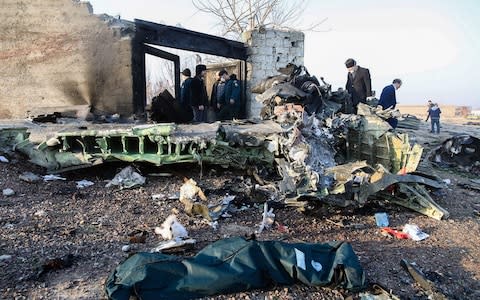 People stand near the wreckage after a Ukrainian plane carrying 176 passengers crashed near Imam Khomeini airport in Tehran - Credit: Rouhollah VAHDATI / ISNA / AFP