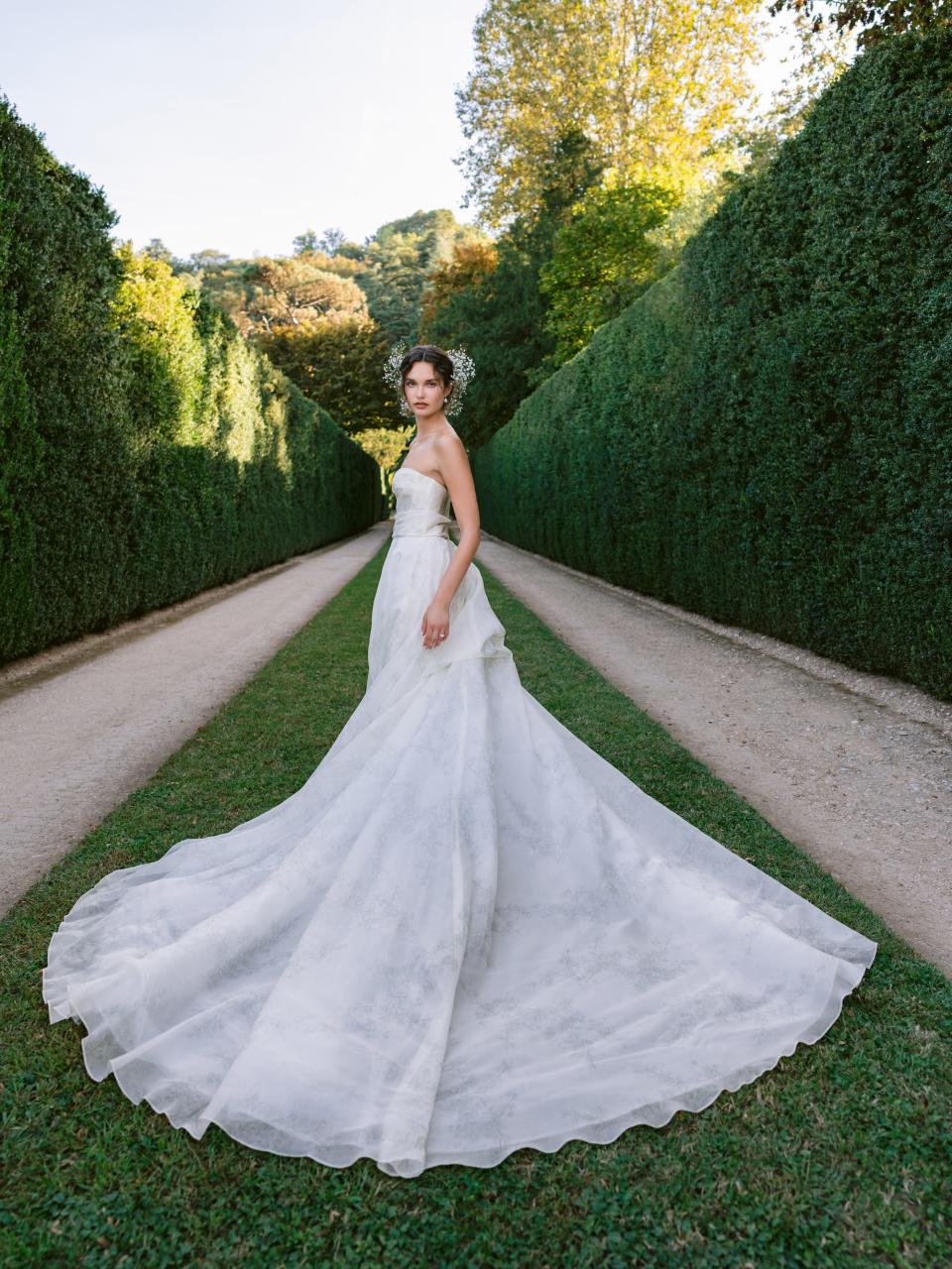 A woman in a wedding dress stands in a field.