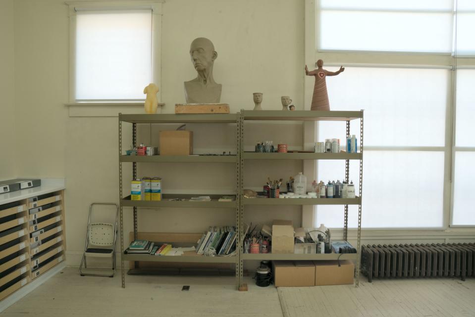 In Chicago’s studio, the clay model she sculpted for a bust of a woman that was later cast in half glass, half bronze, and the model for a wood figure called “Find it in your heart” from her series “Resolutions: A Stitch in Time.” The storage cabinets on the left hold work for an upcoming show at the National Museum of Women in the Arts.