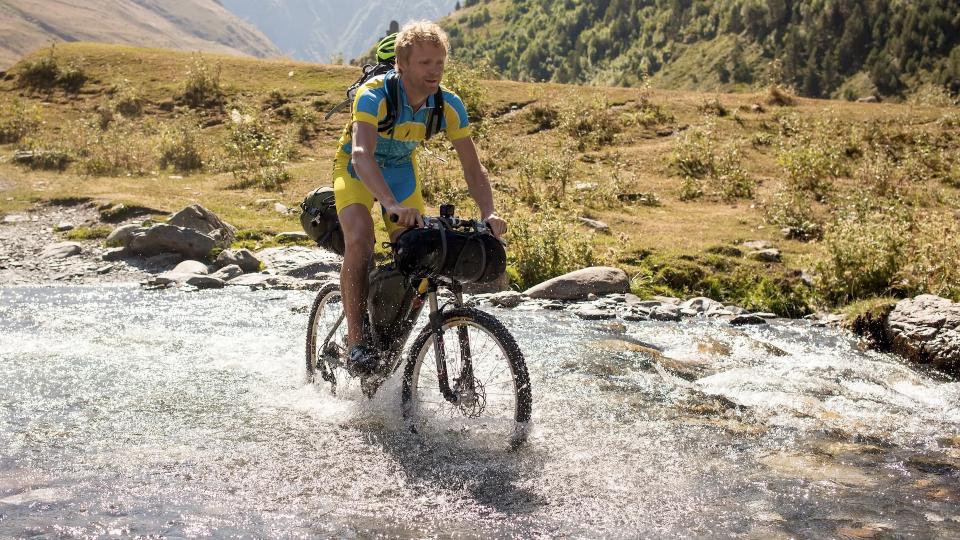 Bikepacker riding through river