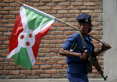 A policewoman carries a Burundi flag during a protest against President Pierre Nkurunziza's decision to run for a third term in Bujumbura, Burundi, May 29, 2015. REUTERS/Goran Tomasevic