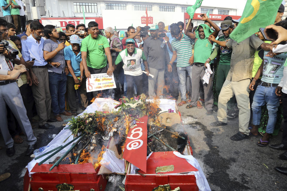 FILE - In this Nov. 15, 2018, file photo, supporters of the United National Party (UNP) and ousted Prime Minister Ranil Wickremesinghe burn coffins to represent the death of democracy during a protest against the government of disputed Prime Minister Mahinda Rajapaksa in Colombo, Sri Lanka. Government dysfunction and an intelligence failure that preceded the Easter Sunday bombings that killed 253 people in Sri Lanka are traced to simmering divisions between the president and prime minister after a weekslong political crisis that crippled the country last year. (AP Photo/Rukmal Gamage, File)