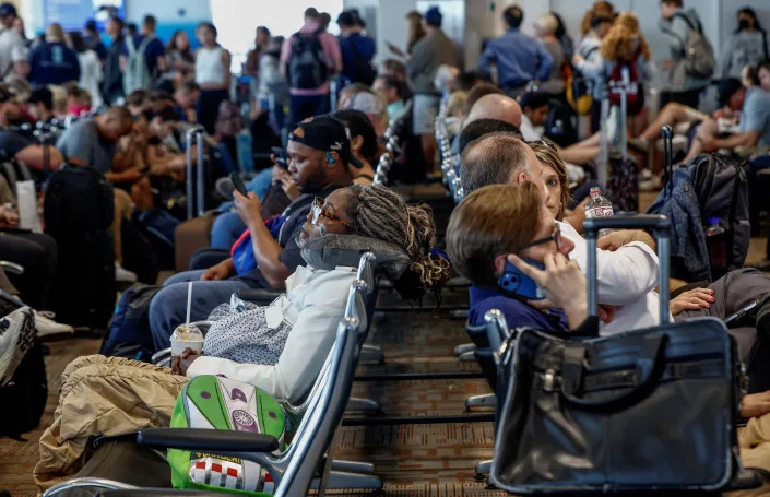 An overcrowded airport lounge with lines of travelers in the background.