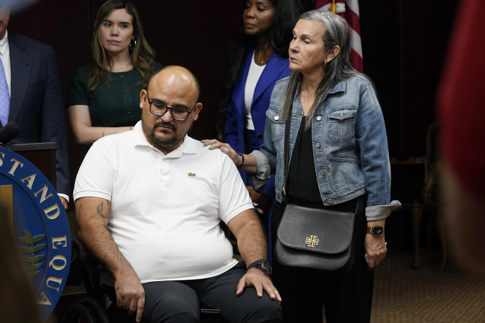 Michael Ortiz listens during a news conference regarding a lawsuit against a police officer Wednesday, March 1, 2023, in Fort Lauderdale, Fla. Ortiz is suing after being paralyzed by a Hollywood, Fla., police officer who mistook his handgun for a taser and shot him in the back. Next to him is his mother Betty Ortiz is at right. (AP Photo/Marta Lavandier)