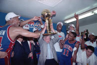 Detroit Pistons team owner Bill Davidson holds the Larry O'Brien Trophy surrounded by his players following their NBA championship victory over the Los Angeles Lakers in game 4 in Inglewood, Ca., June 13, 1989. From left are, Rick Mahorn, Davidson, John Salley, and Isiah Thomas (11). Detroit completed the fifth sweep in NBA Finals history with their 105-97 victory. (AP Photo/Doug Pizac)