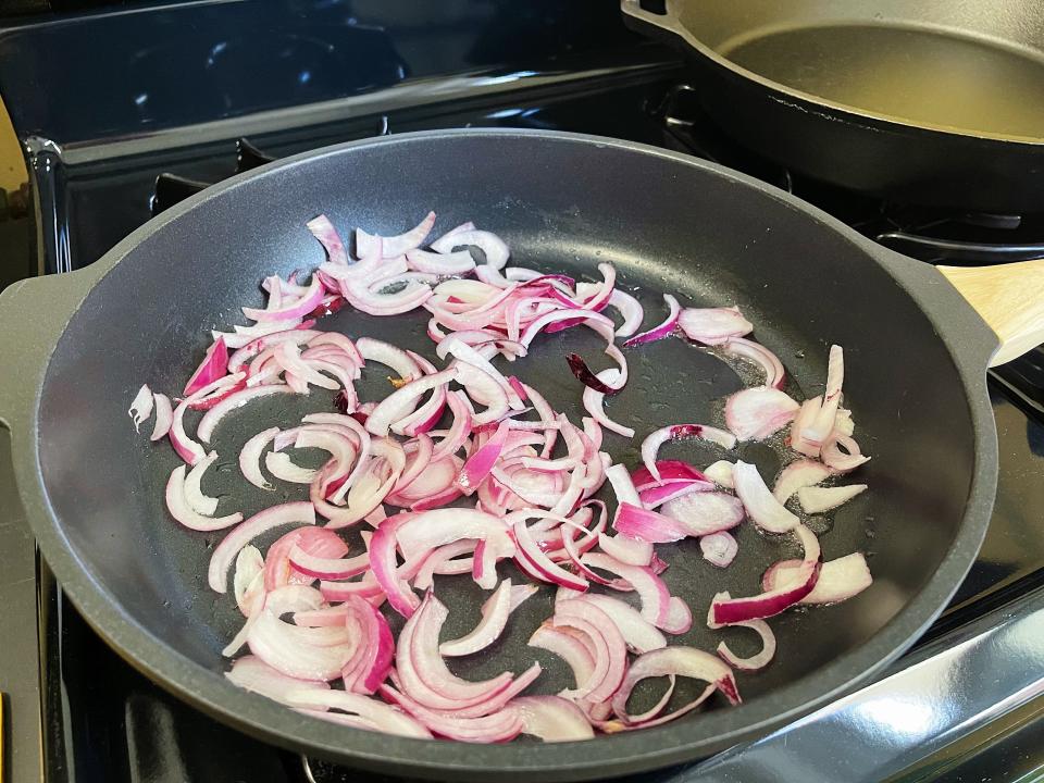 red onion slices cooking in a black pan