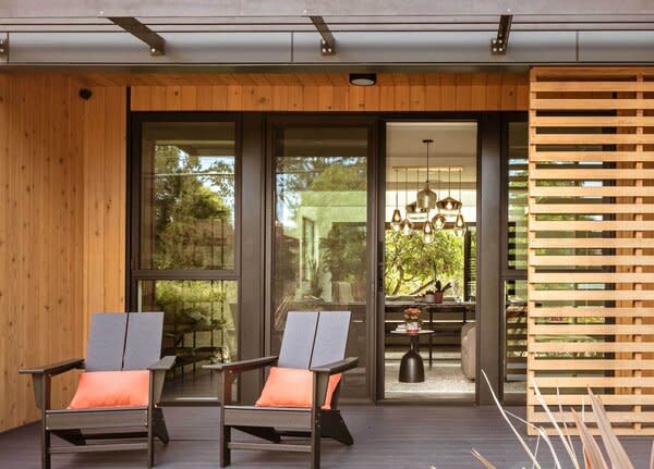 The covered porch is furnished with comfortable seats that allow the residents to engage with neighbors, while the timber screen helps maintain privacy for the interior.